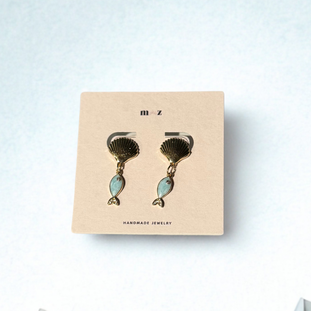 Pair of shell-shaped earrings on a 'm z' branded card against a light background